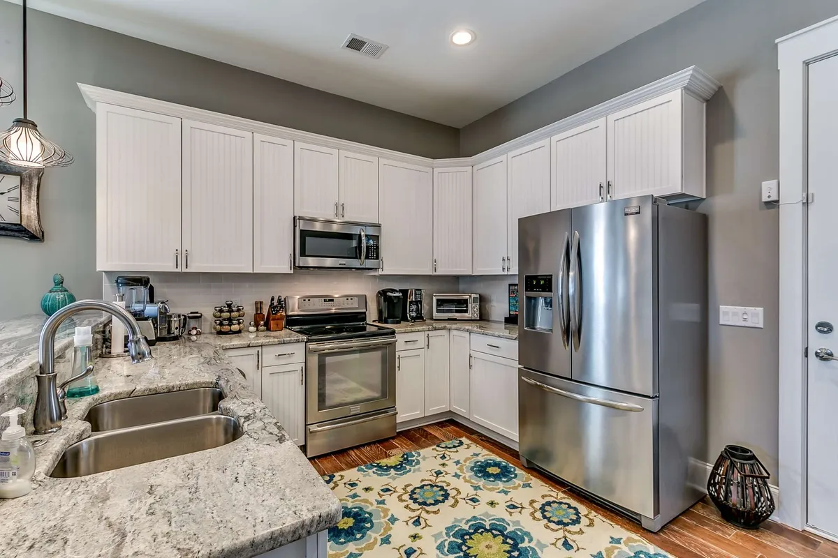 A stylish, functional kitchen with a granite countertop, stainless steel appliances, and a colorful area rug is at the heart of a spacious, inviting home. The scene suggests a perfect setting for cooking, entertaining, or gathering with family and friends, blending comfort and practicality.