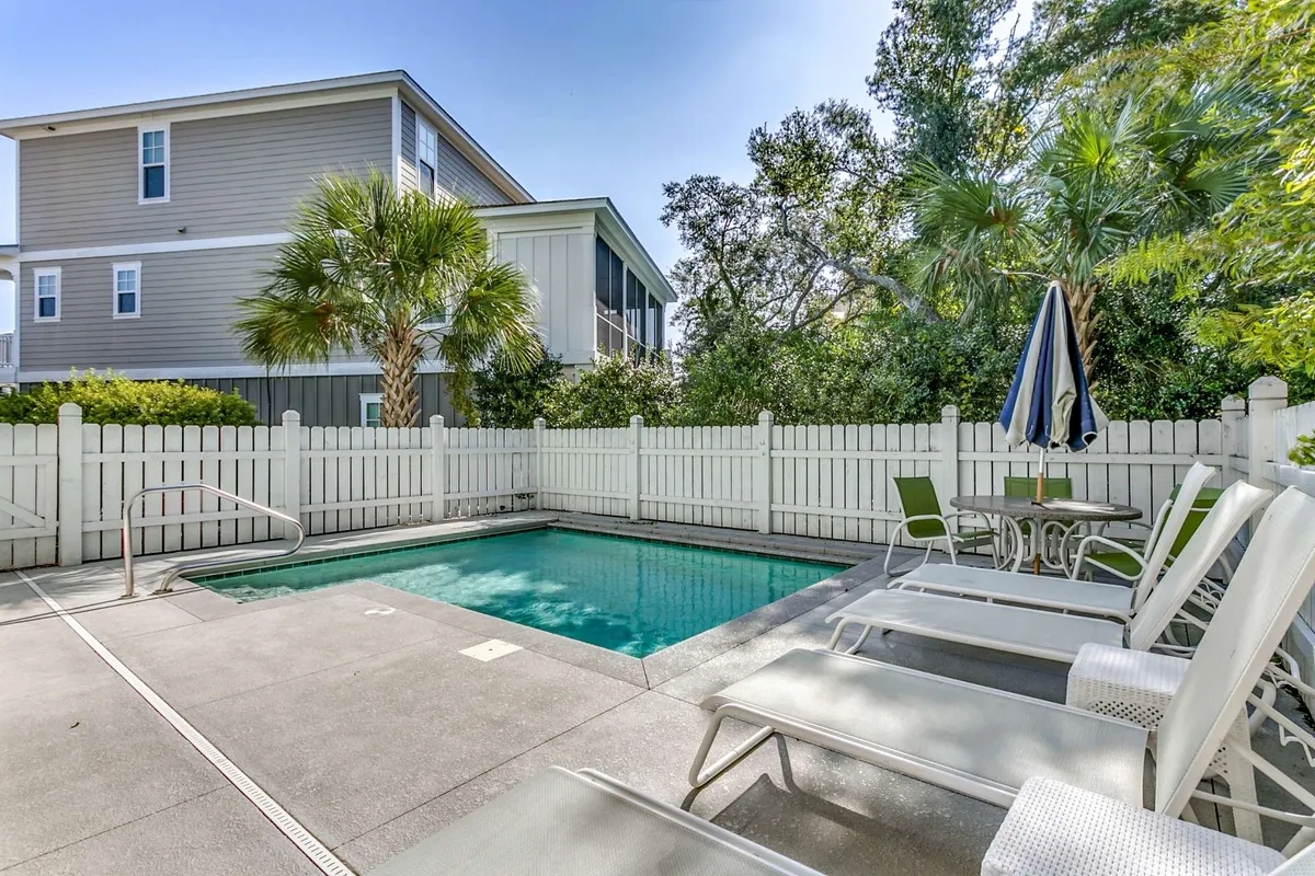 An inviting private pool scene featuring ample lounge chairs along the deck, palm trees that evoke a vacation vibe, and a secure fenced area for added privacy. The image suggests ample space for sunbathing, poolside gatherings, and evening relaxation.