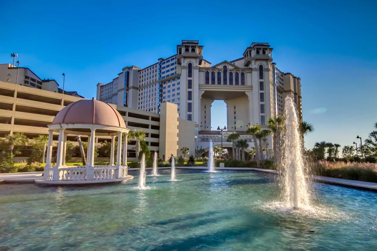 This exterior image features a picturesque fountain and gazebo set against inviting resort-style architecture. The tranquil setting suggests spaces to unwind and gather, while the water element evokes relaxation after active days.