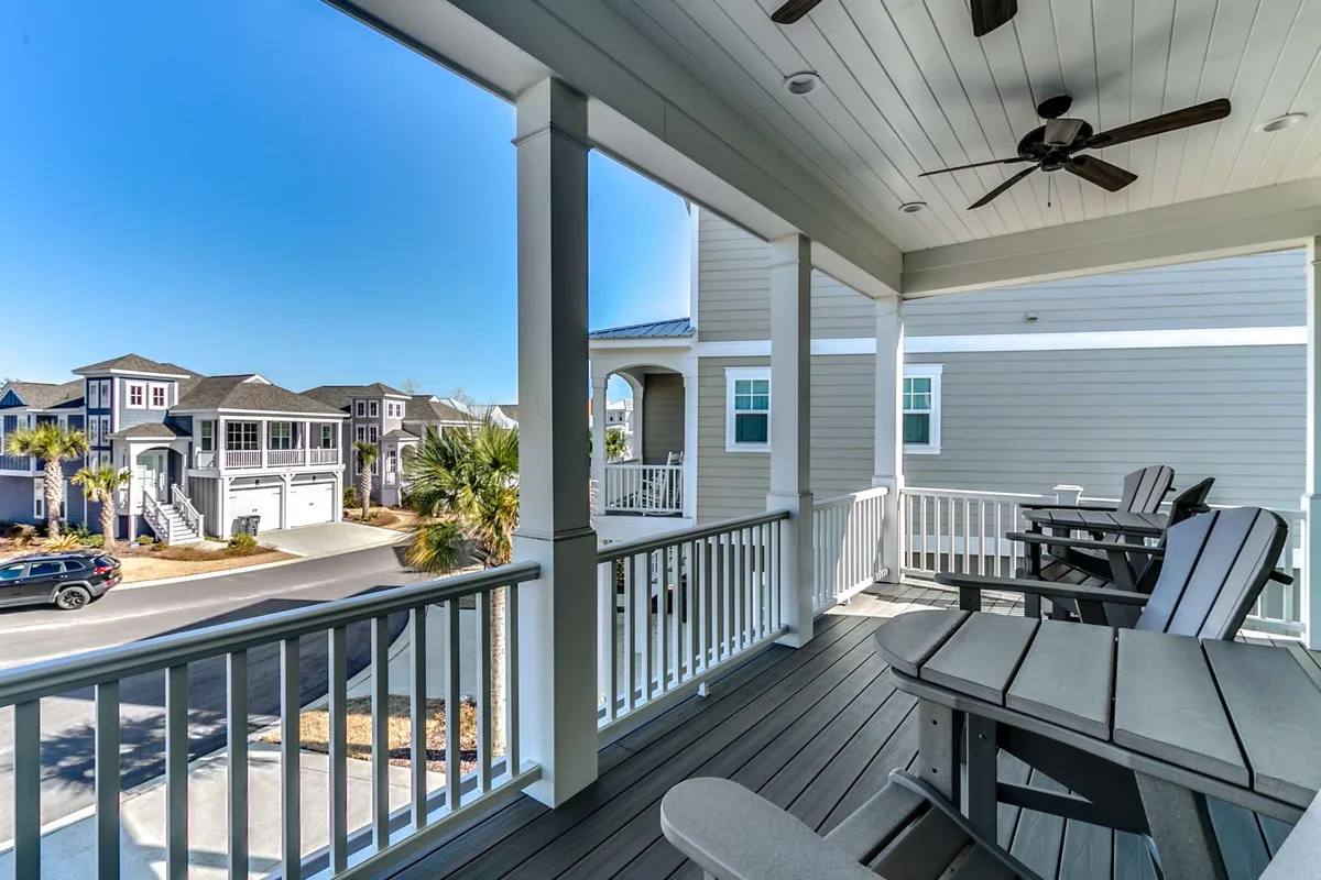 An exterior view featuring a pair of Adirondack chairs on a spacious deck shaded by palm trees, overlooking a quiet street. The setting is perfect for enjoying sunset drinks, socializing outdoors, or simply soaking up the serene atmosphere.