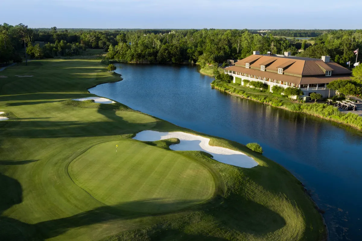 A scenic golf course featuring a lush green, a serene water body, and a well-maintained clubhouse. The scene is peaceful yet active, with visible sand traps and a successful putt, inviting both leisure and sporting activities. The setting is ideal for adults looking to unwind or enjoy a round of golf as part of their resort experience.